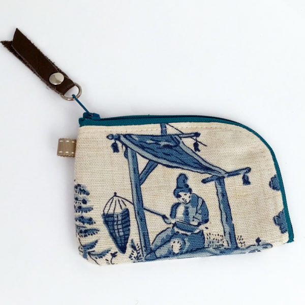 image of a small woman's person fishing under a shelter blue toile linen zipper card wallet on its one side