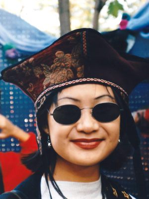 Close up of woman with glasses wearing a red Four Corner Hat.