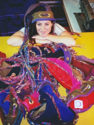 A pile of Squid Toques in front of a women wearing a Squid Toque