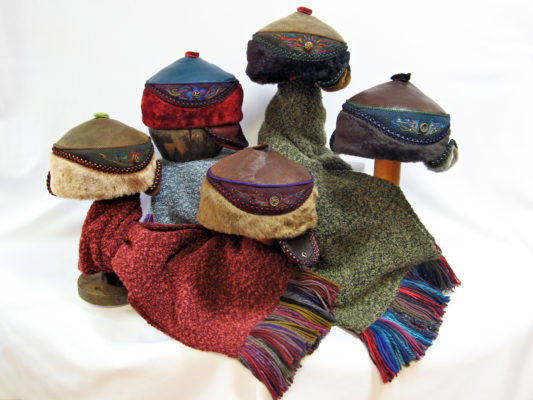 5 Anoushka design hats sitting on top of Gwendolyne's hand fringed boucle knit scarves.