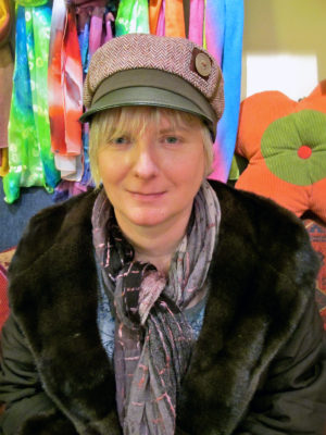 A woman wearing her new olive and red Abbey Road Cap sitting in the shop