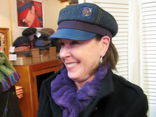 A close up of happy customer wearing her new Abbey Road Cap in blue and purple colours.