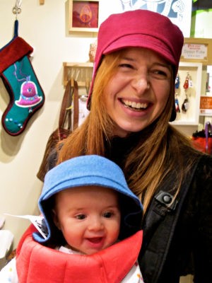 Happy new customer wearing her new pink Amelia Hat with her baby modelling a blue one.