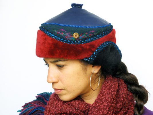 A close up of a woman wearing a red and blue Anoushka Design Hat
