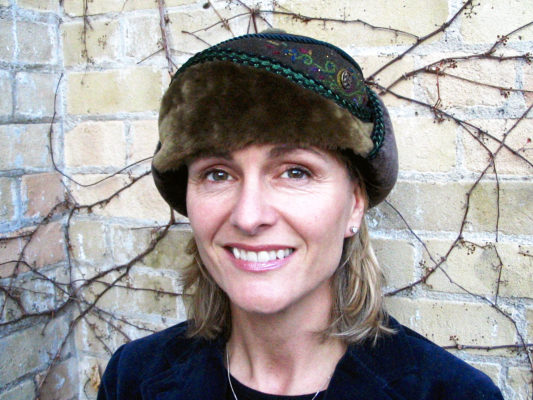 A close up of a woman wearing her new olive green Anoushka Design Hat