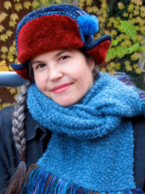 A close up of a woman wearing a blue and red Pom Pom Hat