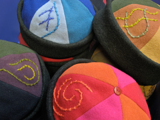 4 colourful Bean Toques in a pile showing off the embroidered motif