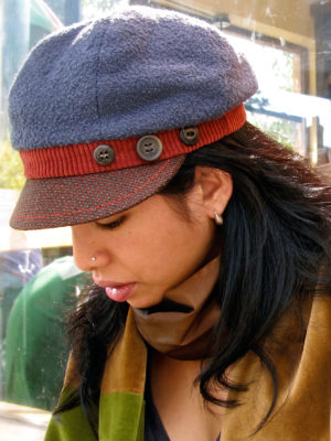 A close up of a woman wearing a grey papaya and brown cap.
