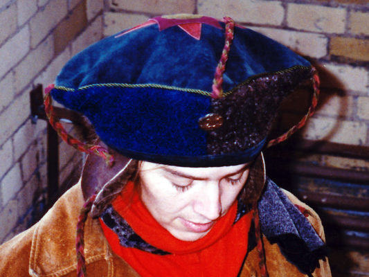 A close up of a woman looking down wearing a blue Theodore Hat