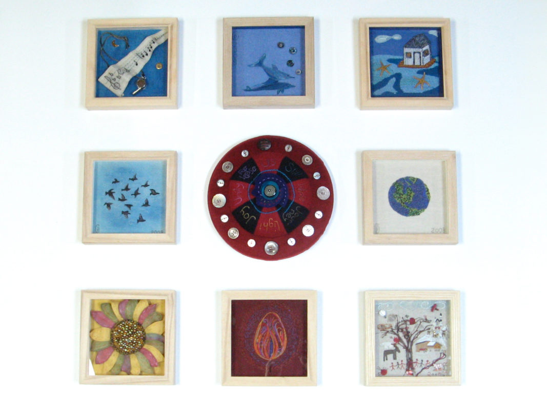 framed embroidery works around a large pin cushion