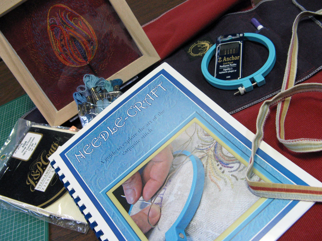 Image of the Atelier Gwendolyne Needle Craft booklet embroidery hoop, embroidery floss and a Fire artwork framed