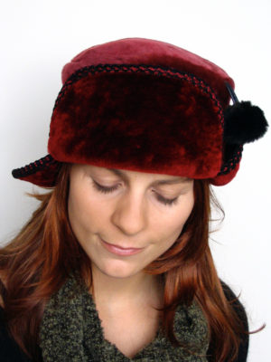 A close up of a woman wearing a red and black Pom Pom Hat