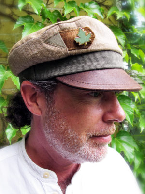 A close up of customer wearing his new custom ordered Robin Cap with a leather peak and a leaf brooch