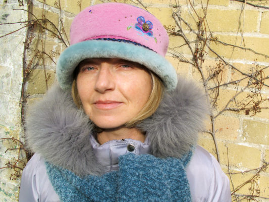 A close up of woman wearing a soft pink Rusalka Hat with a sea foam blue coloured fur rim