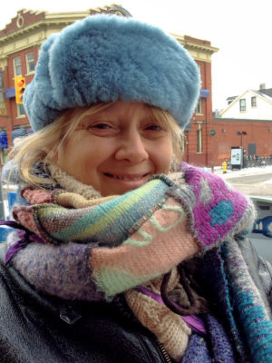 A close up of a happy customer wearing her new light blue Winter Wave hat on a woman outside