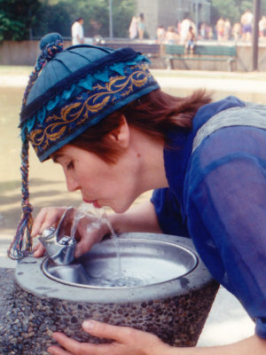 Close of Gwendolyne drinking from a fountain of water wearing a blue silk cap.