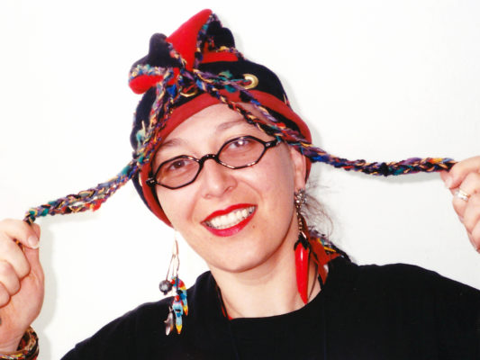 Close up of woman wearing a red and black Squid Toque with long tassels.