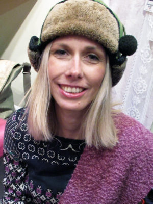 A close up of a happy woman wearing her Pom Pom shearling hat.