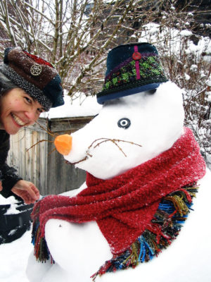 Gwendolyne tying a scarf around the neck of a Snow Rat wearing a Estonian hat.