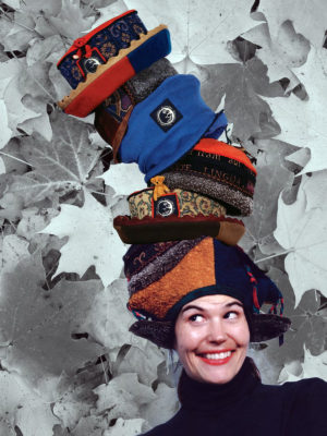 Gwendolyne smiling with 6 of her hat designs on her head.